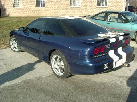 1995 Ford Probe - A blue 1995 Ford Probe GT is parked outside a brick building, with a teal car in the background.