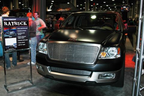 1991 Ford Taurus - Black pickup truck with custom grille and hood emblem on display at an auto show.