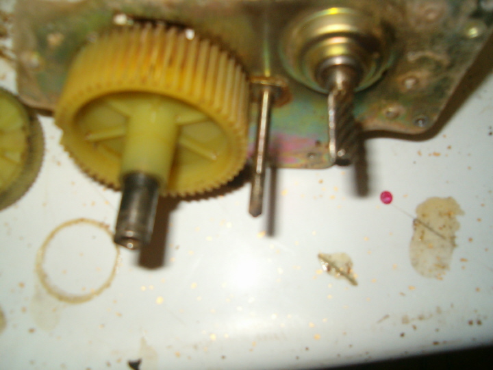 Yellow plastic speedometer drive gear and metal driven gear on a worktable with parts and reference circles