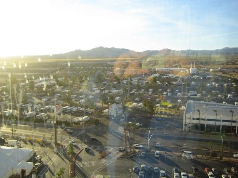 1990 Ford Bronco - elevated window view over a desert town showing RV lots, streets, parking, and distant mountains in low sun.
