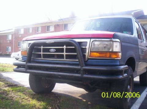 1988 Ford Bronco - This Ford truck features a prominent bull bar on its front end, with a two-tone blue and red paint scheme.