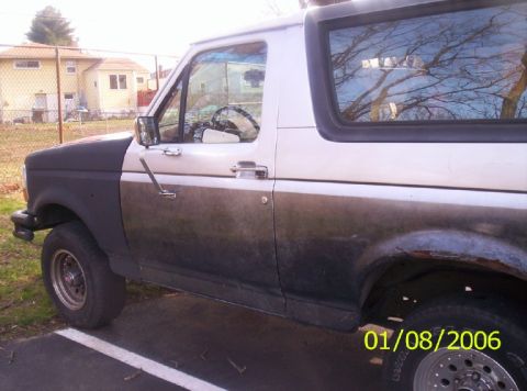 1988 Ford Bronco - This two-tone Ford Bronco shows significant wear and rust on its side panel and fender.