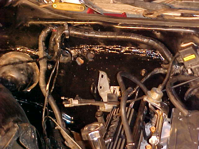 Dirty, oil-covered engine bay with hoses, wiring and brackets