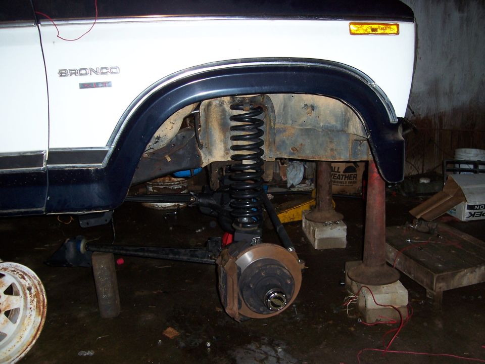 Bronco badge on white body, front wheel removed, suspension components visible