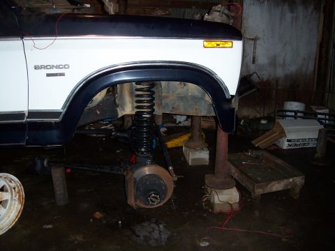 1983 Ford Bronco - Front suspension of a 1983 Ford Bronco undergoing work, showing the coil spring and brake components.