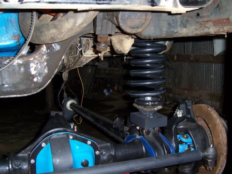 1983 Ford Bronco - Undercarriage view of a vehicle's modified suspension and axle components, showing a large coil spring and steering linkage.
