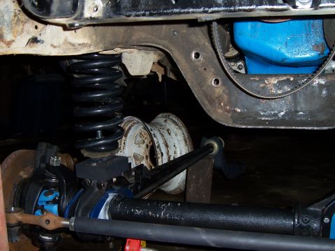 1983 Ford Bronco - Close-up view of front axle and suspension components, including a black coil spring and blue-colored parts.
