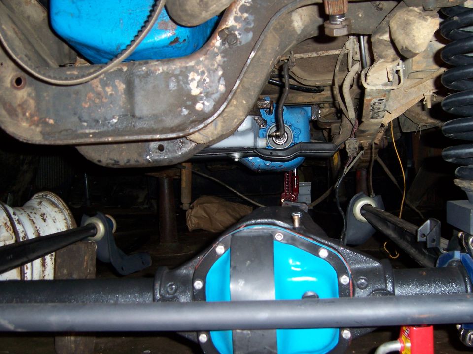 Blue-painted differential cover and steering box on a truck front axle underneath