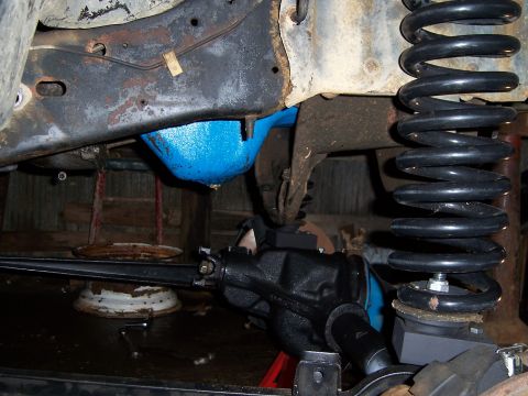 1983 Ford Bronco - Close-up view of a vehicle's undercarriage, highlighting a blue differential cover and a large coil spring, likely part of a suspension mod…