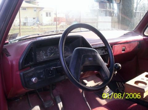 1988 Ford Bronco - The interior of a 1988 Ford Bronco, its dashboard, steering wheel, and floor shifter, is visible in this photograph.