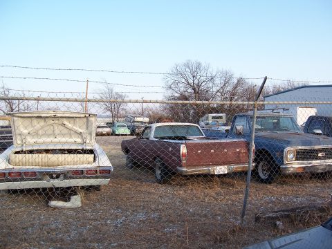 1979 Ford Ranchero - A brown Ford Ranchero sits in a junkyard next to other vehicles.