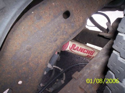 1988 Ford Bronco - Close-up of a Rancho RS5000 shock absorber mounted to a rusty vehicle frame.