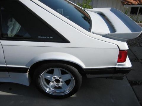 1993 Ford Taurus - Rear view of a white coupe, identified by 'Mustang' badging, a prominent rear spoiler.