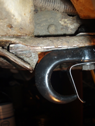 1985 Ford Bronco II - Close-up view of a black tow hook mounted to a rusty vehicle frame.