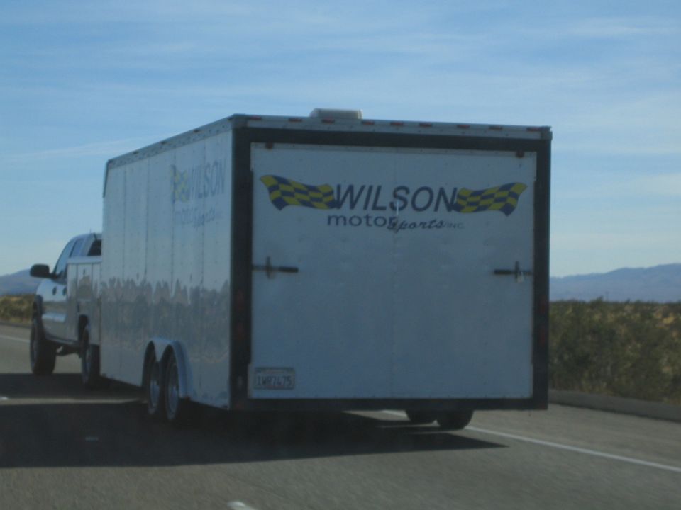 White enclosed Wilson Motorsports car-hauler trailer towed on a desert highway