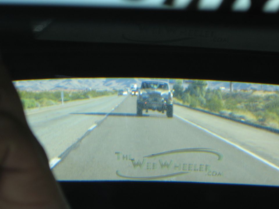 View through a rear window with WebWheeler logo of a Jeep following on a highway