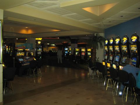 1990 Ford Bronco - Interior of a casino floor showing rows of glowing slot machines, a KENO sign, and a few seated patrons under low lighting.