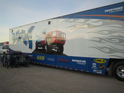 1990 Ford Bronco - long enclosed race trailer wrapped with Fabtech, Toyo Tires, Magnaflow and other sponsor graphics depicting a lifted truck.