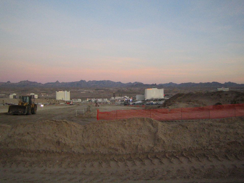 Desert construction site with a wheel loader and orange fencing at dusk