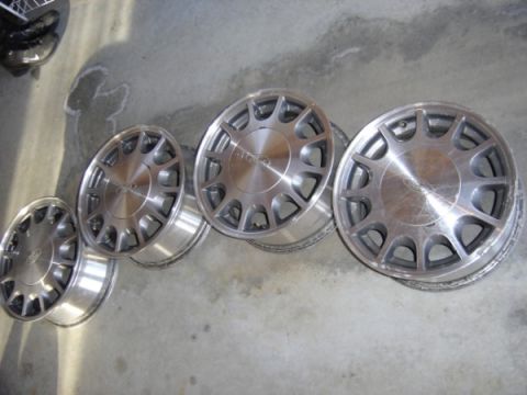 1999 Ford Taurus - Set of four aluminum alloy wheels displayed on a concrete floor.