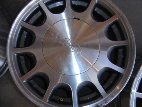 1999 Ford Taurus - A close-up view of a silver alloy wheel with the Ford emblem in the center.