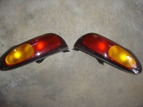 1999 Ford Taurus - A pair of red and amber tail lights are displayed on a concrete surface.