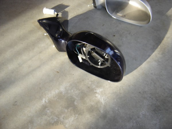 Disassembled car side mirror assembly with wiring visible