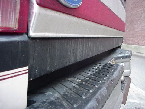 1993 Ford Bronco - Detail shot of the rear bumper and lower tailgate of a truck, showing wear and dirt.