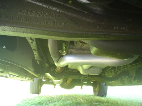 2005 Ford Excursion - The underside of a vehicle is visible, displaying its exhaust system and frame components. Text on the frame reads 'DO NOT BEND-HEAT-WELD'.