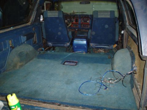 1984 Ford Bronco - The rear cargo area and seats of a blue SUV are visible, with loose wires on the floor.