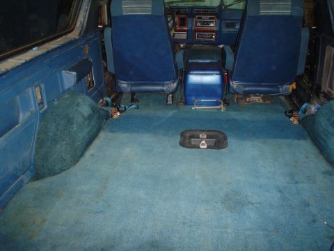 1984 Ford Bronco - The interior of a vehicle with blue carpeting and seats, showing the dashboard and center console.