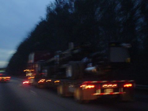 1966 International School Bus - A truck hauls logs on a highway as daylight fades.