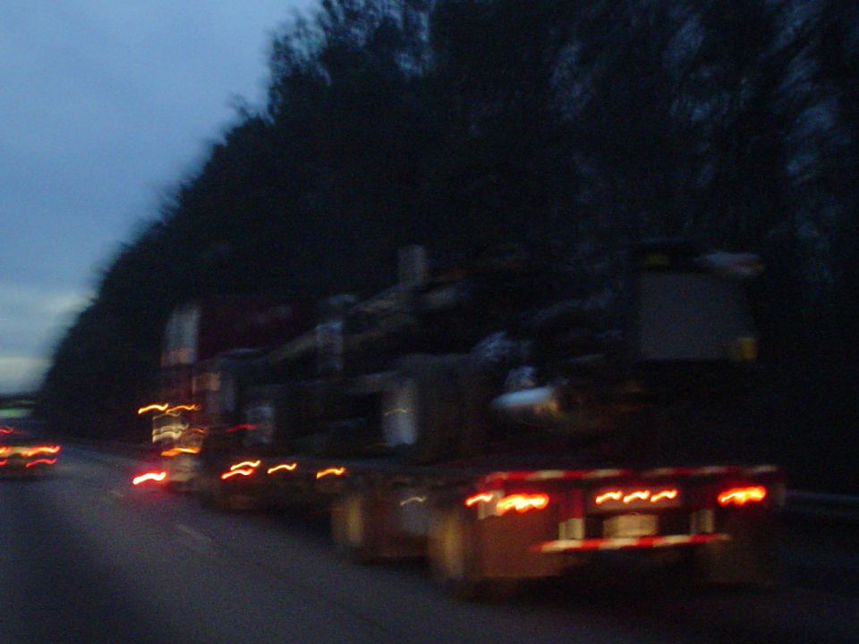 Truck with trailer carrying logs, seen from the side at dusk
