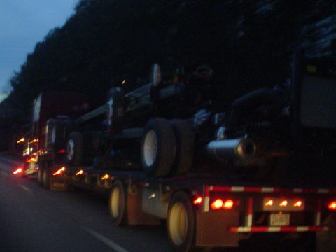 1966 International School Bus - Several trucks are seen on a highway as dusk settles, their taillights glowing in the dim light.