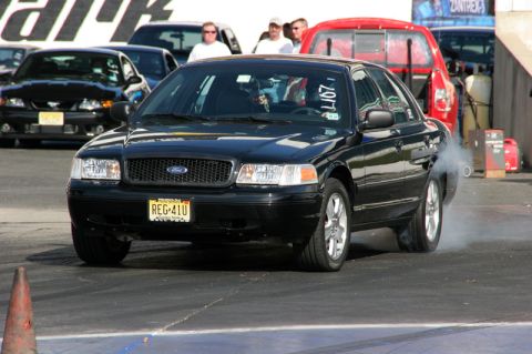 2004 Ford Crown Victoria - A black 2004 Ford Crown Victoria is seen on the drag strip, kicking up smoke from its tires.