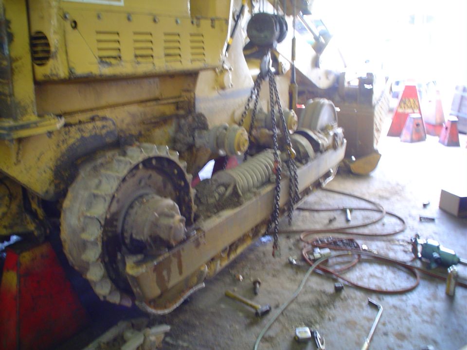 Heavy machinery with tracks and chains being worked on in a garage