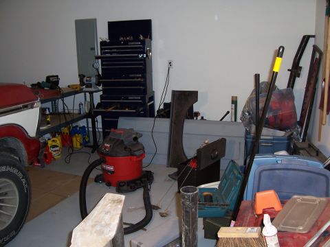 1978 Ford Bronco - A cluttered garage scene with various tools, storage bins, and vehicle components visible.