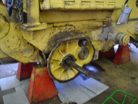 1966 International School Bus - Close-up of a heavy equipment drivetrain component being worked on, supported by red jack stands.