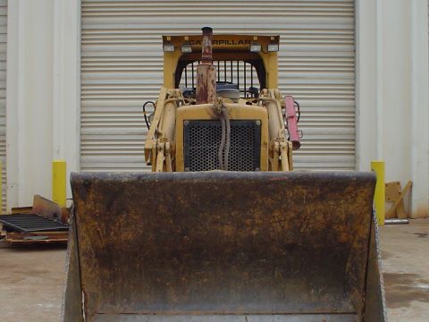 1966 International School Bus - A yellow bulldozer with a front blade is parked in front of a large garage door.