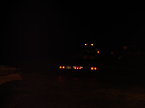 1992 Ford Bronco - The rear lights of a truck and trailer are visible in the dark.