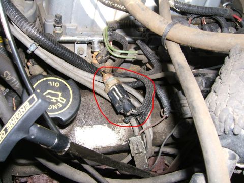 1990 Ford Bronco - Close-up view of an engine sensor and associated wiring, with an oil cap visible in the foreground.