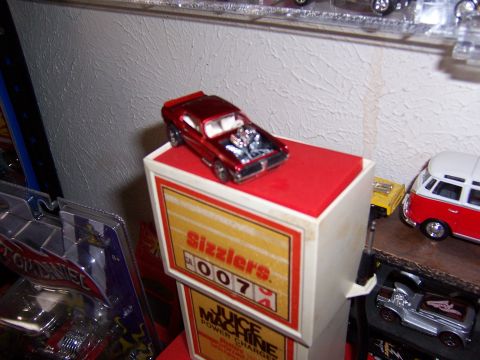1979 Ford Ranchero - A red toy car with its hood open sits atop a display box labeled 'Sizzlers Juice Machine'.