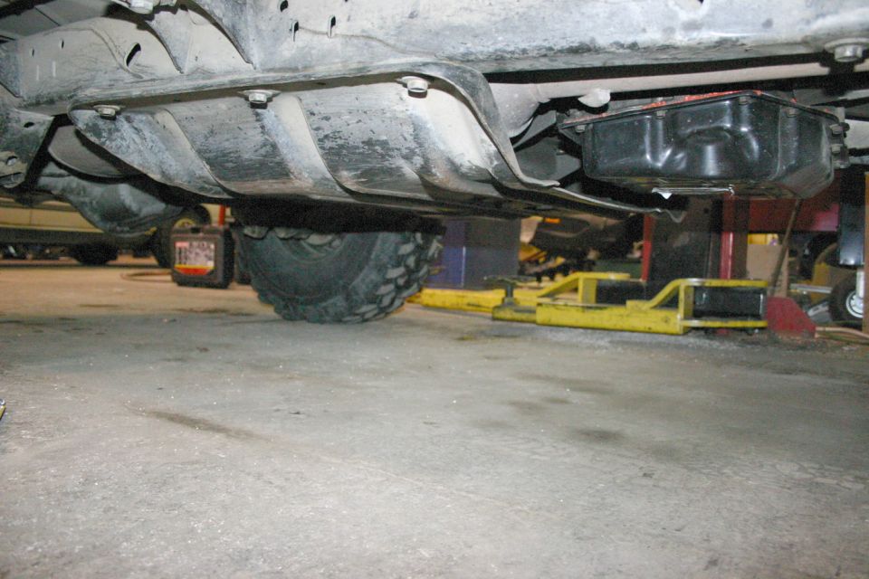 Underbody view showing a transmission pan and part of a tire. Vehicle is on a lift