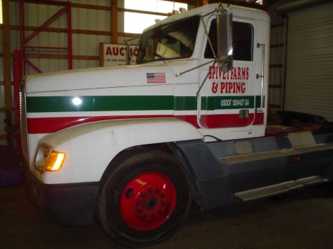 1966 International School Bus - Semi-truck cab with "SPIVET FARMS & PIPING" livery is parked indoors.