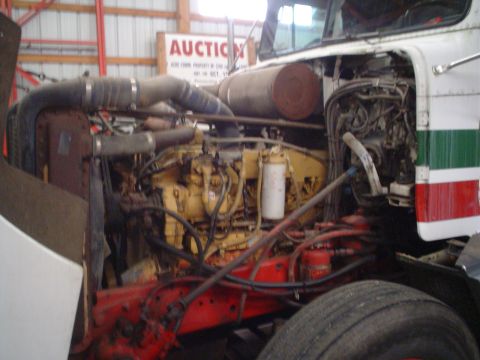 1966 International School Bus - The engine compartment of a truck is shown, a large yellow engine and exhaust system.