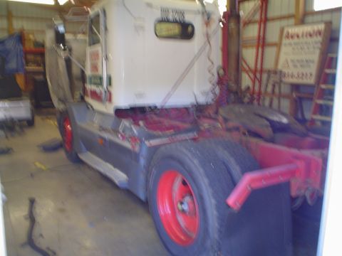 1966 International School Bus - This semi-truck tractor has dual rear wheels and red-painted rims, seen in a workshop setting.