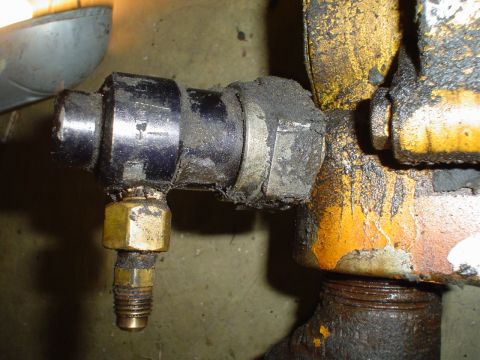 1966 International School Bus - This close-up shows a greasy mechanical part with a brass fitting, likely a component from a larger machine.