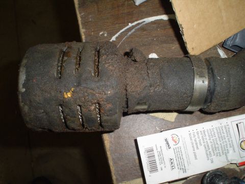 1966 International School Bus - Close-up of a dirty air filter attached to an exhaust pipe, with product packaging in the foreground.
