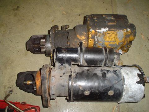 1966 International School Bus - Two starter motors are shown, one with yellow housing and the other with black housing, resting on a floor.