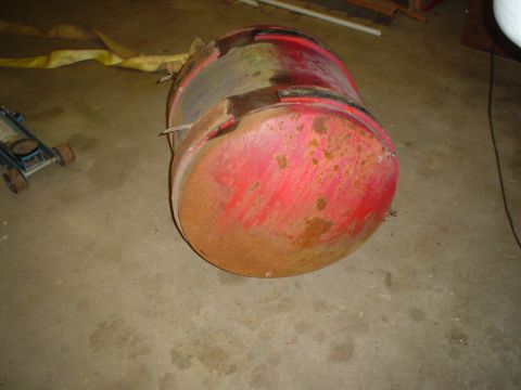 1966 International School Bus - A large, red, cylindrical fuel tank shows significant rust and wear, resting on a concrete surface.